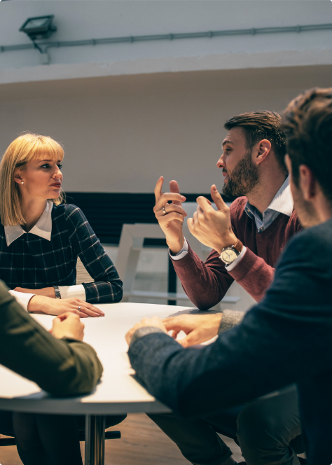 Photo of group of business workers sat around a desk discussing services